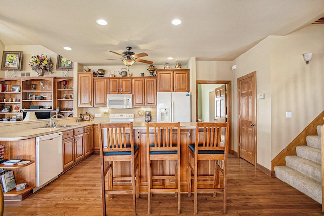 kitchen featuring light countertops, white appliances, a sink, light wood-style floors, and ceiling fan