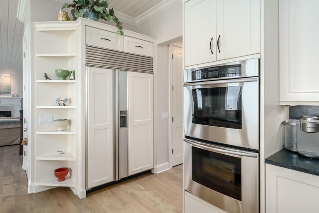 kitchen featuring paneled built in fridge, crown molding, open shelves, stainless steel double oven, and light wood-type flooring
