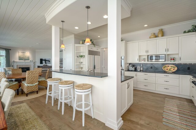 kitchen featuring crown molding, stainless steel microwave, dark countertops, paneled built in fridge, and open shelves