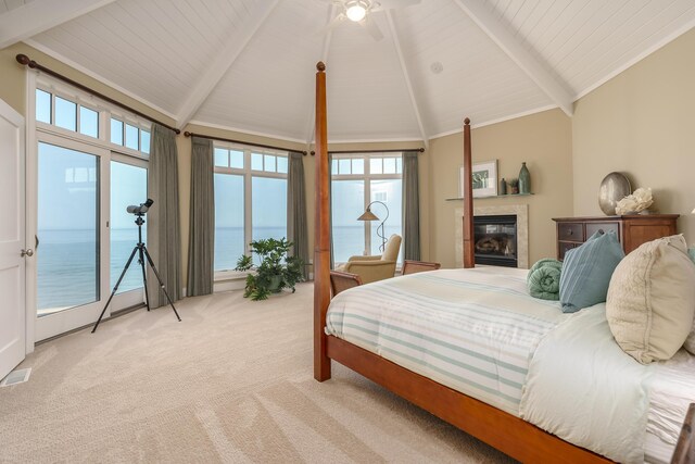 bedroom with light carpet, vaulted ceiling with beams, a tile fireplace, and access to outside
