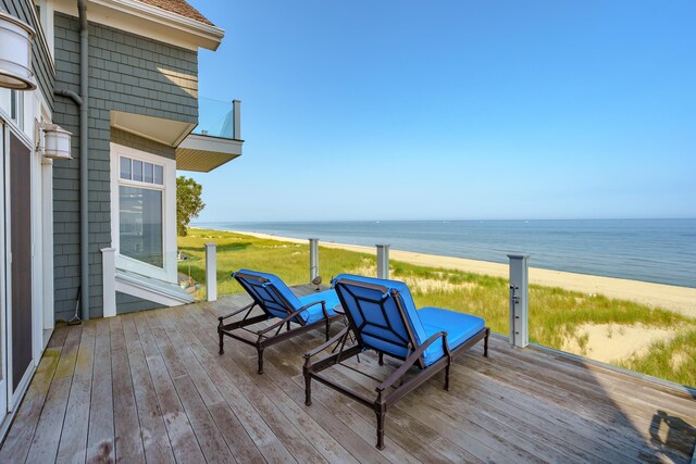 wooden deck with a water view and a beach view