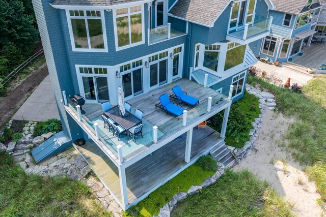 back of property with a deck and roof with shingles