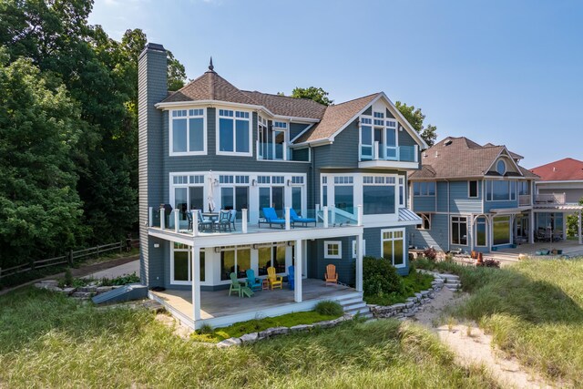 back of house featuring a balcony, a chimney, a wooden deck, and a patio area