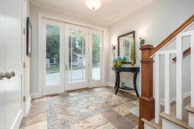 doorway to outside with stone tile flooring, ornamental molding, baseboards, and stairway