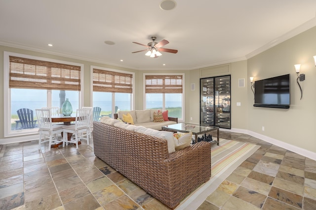 living area featuring baseboards, ornamental molding, a wealth of natural light, and a ceiling fan