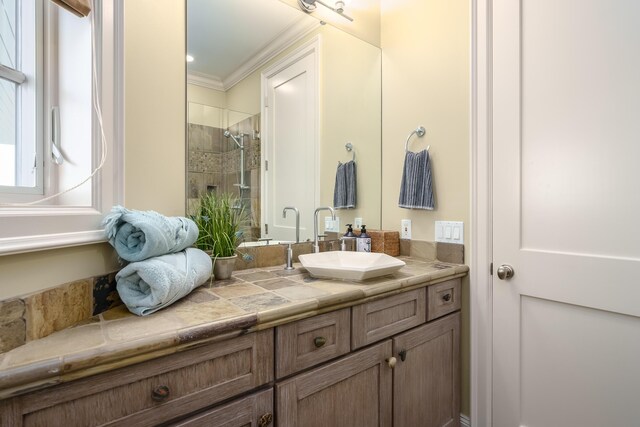 bathroom featuring vanity, crown molding, and tiled shower