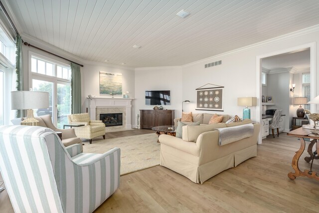 living area featuring wood ceiling, light wood finished floors, a fireplace, visible vents, and ornamental molding