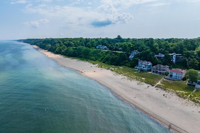 aerial view featuring a water view, a wooded view, and a beach view