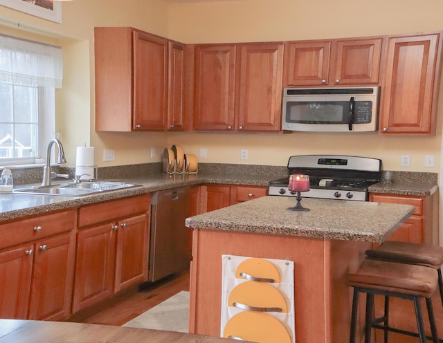 kitchen featuring a sink, a breakfast bar area, a center island, brown cabinets, and stainless steel appliances
