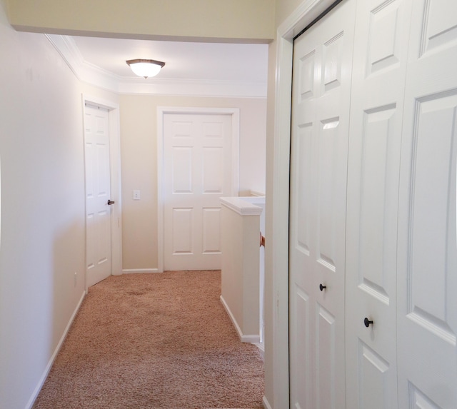 hallway with light carpet, baseboards, and ornamental molding