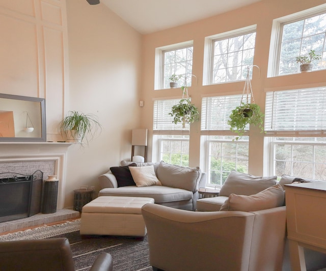 living room featuring a brick fireplace, vaulted ceiling, and a wealth of natural light