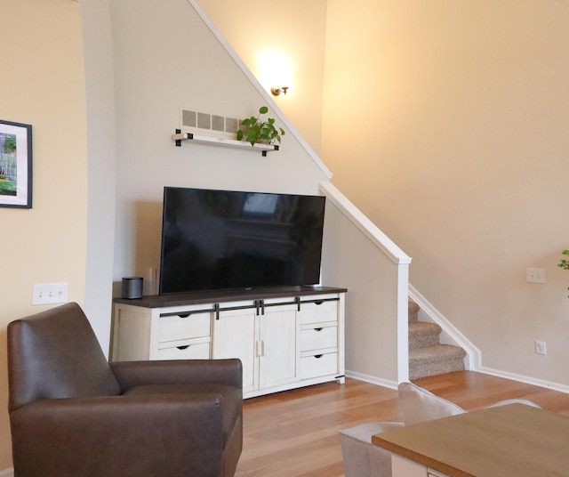 living room with light wood finished floors, stairs, and baseboards