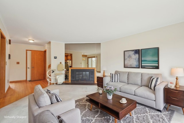 living room featuring crown molding, baseboards, a glass covered fireplace, and wood finished floors