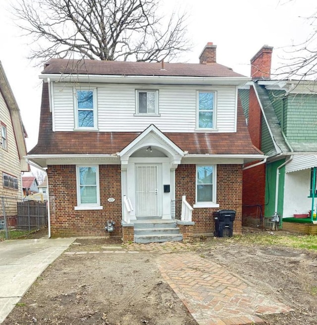 3297 Hazelwood St, Detroit, MI 48206 - view of front of house with fence, brick siding, a chimney, and a shingled roof