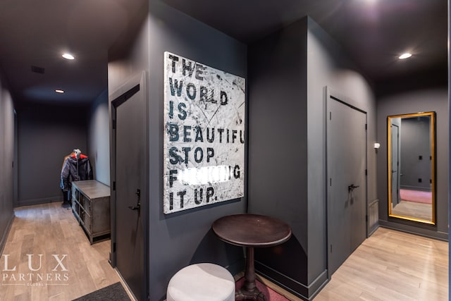 hallway featuring visible vents, baseboards, recessed lighting, and light wood-style floors