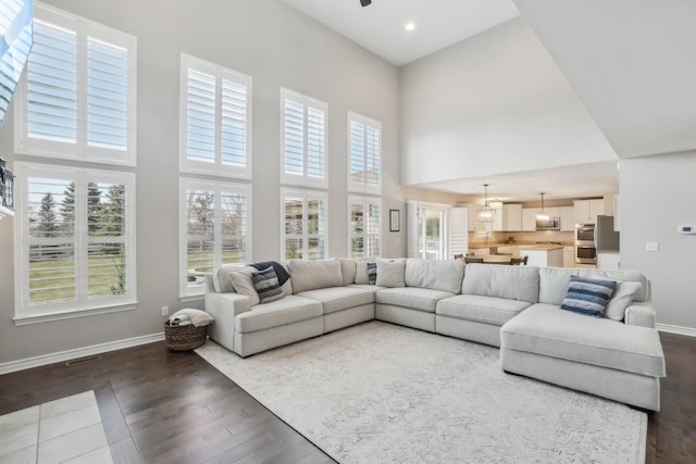 7416 Secretariat Dr, Saline, MI 48176 - living area with a towering ceiling, dark wood-style floors, baseboards, and a healthy amount of sunlight