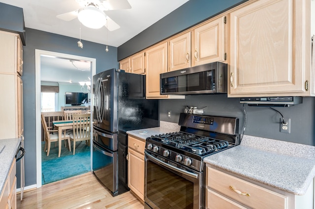 kitchen featuring light brown cabinets, light wood-type flooring, appliances with stainless steel finishes, a ceiling fan, and light stone counters