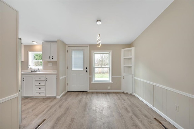 interior space featuring visible vents, light wood-style flooring, a sink, and wainscoting