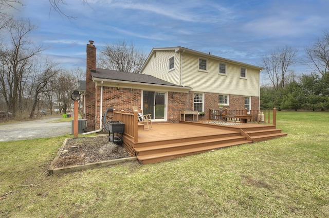rear view of property with a lawn, a chimney, cooling unit, and brick siding