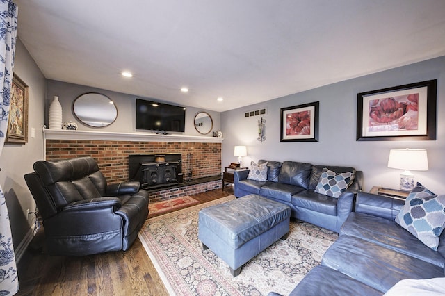 living room featuring visible vents, a wood stove, recessed lighting, and wood finished floors