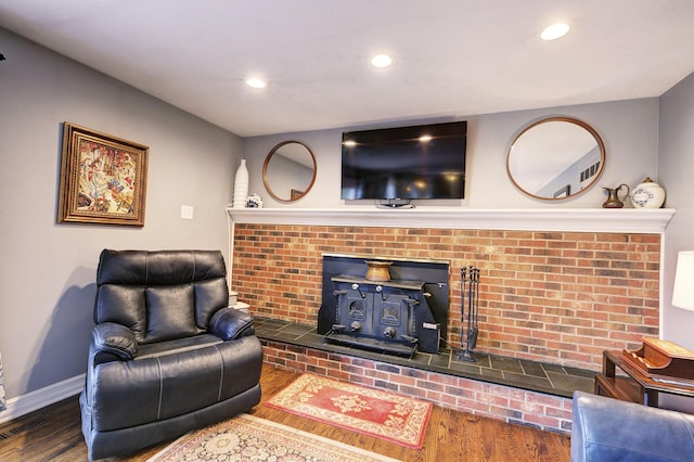 living area with wood finished floors, a wood stove, baseboards, visible vents, and recessed lighting