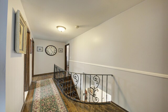 hall with baseboards, an upstairs landing, and wood finished floors