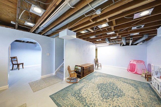 finished below grade area with arched walkways, baseboards, and stairs