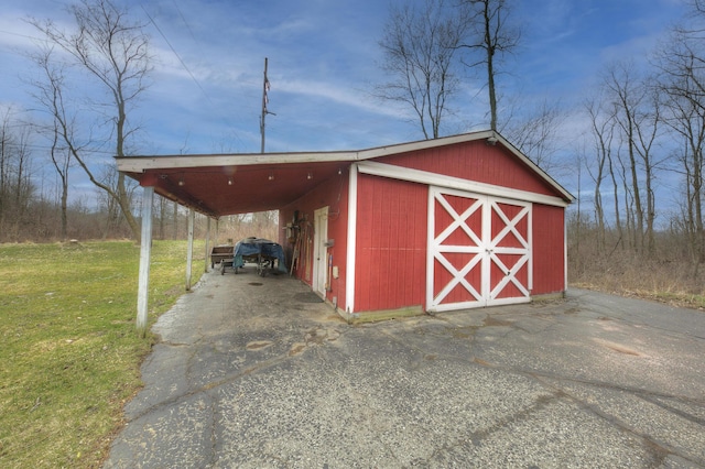 view of outdoor structure with driveway, an attached carport, and an outdoor structure