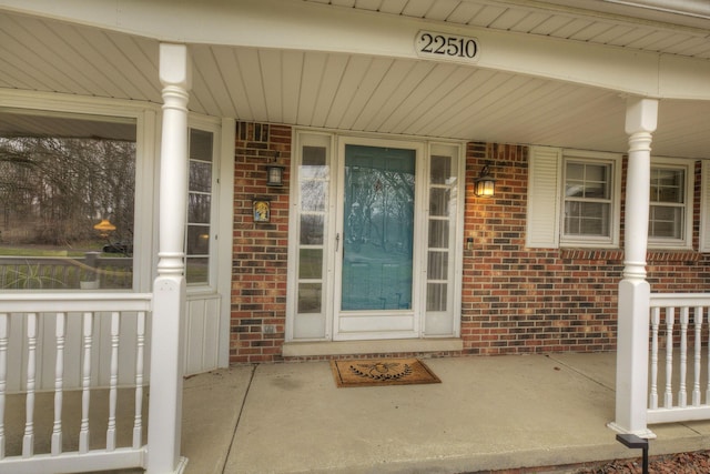 doorway to property with brick siding and a porch