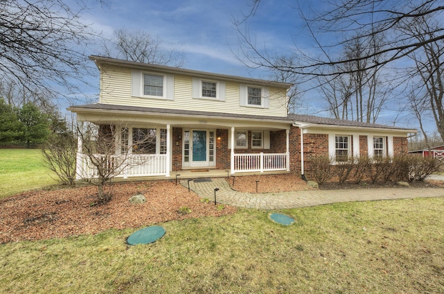 traditional home featuring a front yard, covered porch, and brick siding