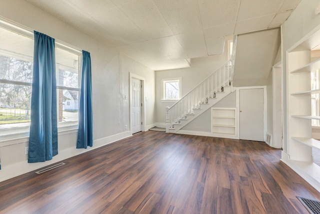 foyer with dark wood-type flooring, stairway, visible vents, and baseboards