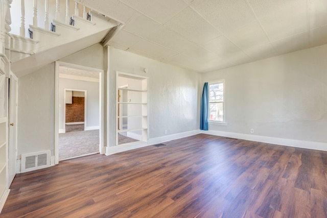 spare room featuring visible vents, baseboards, and dark wood-style flooring