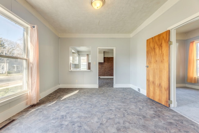 spare room featuring visible vents, baseboards, stone finish floor, and a textured ceiling
