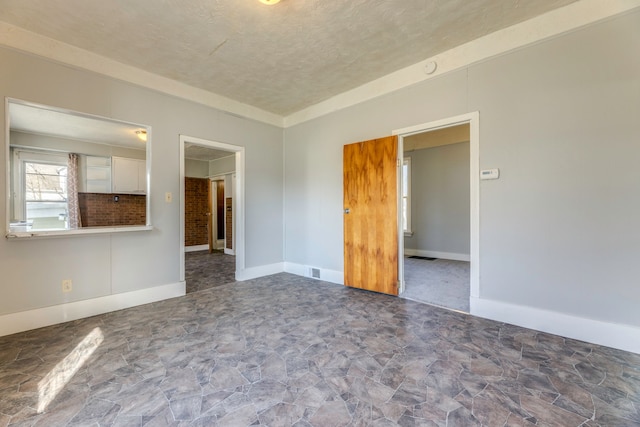 empty room featuring baseboards, stone finish floor, and a textured ceiling