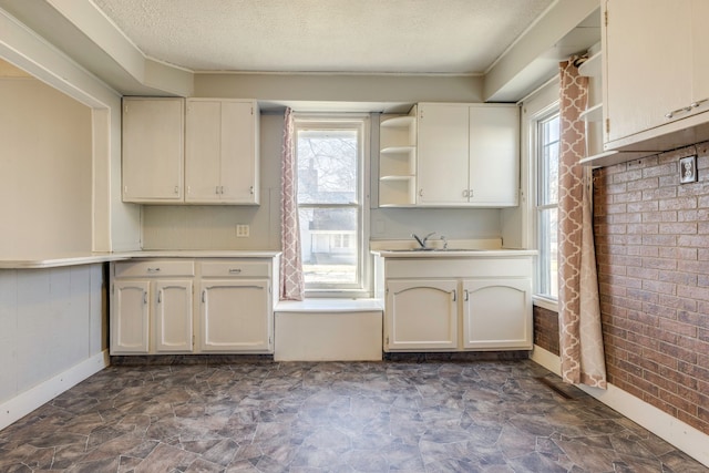 kitchen featuring open shelves, a textured ceiling, a healthy amount of sunlight, and a sink