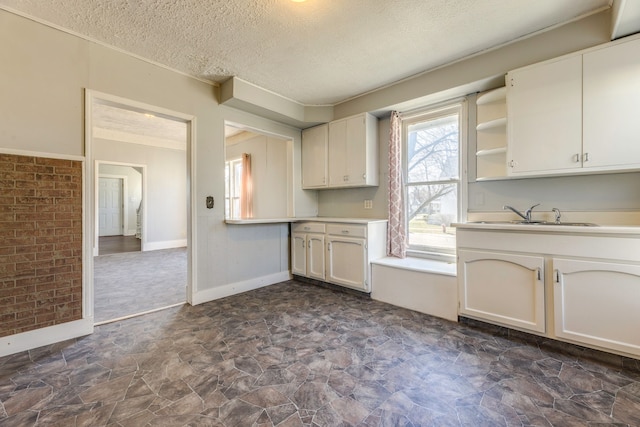 kitchen featuring light countertops, stone finish floor, a textured ceiling, and a sink