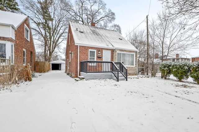 snow covered rear of property with fence, an outdoor structure, a chimney, and brick siding