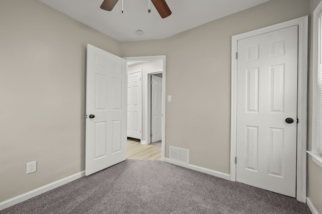unfurnished bedroom featuring a ceiling fan, visible vents, light colored carpet, and baseboards