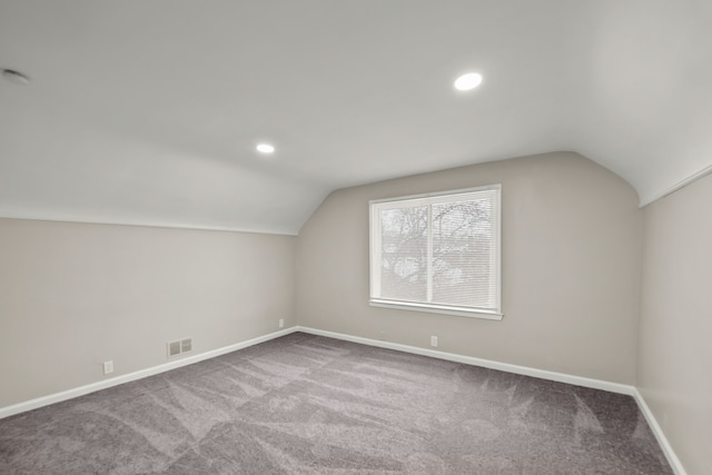 additional living space with visible vents, carpet flooring, vaulted ceiling, and baseboards