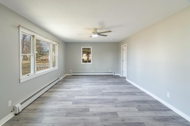 unfurnished room featuring a ceiling fan, wood finished floors, a baseboard radiator, baseboards, and a baseboard heating unit