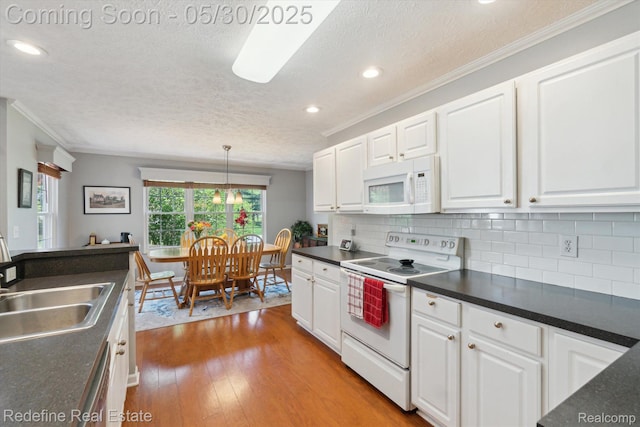 328 Split Rail Rdg, Williamston, MI 48895 - kitchen featuring white appliances, a textured ceiling, dark countertops, white cabinets, and light wood finished floors