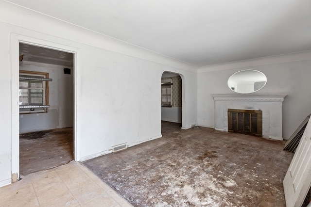 unfurnished living room with visible vents, arched walkways, and a glass covered fireplace