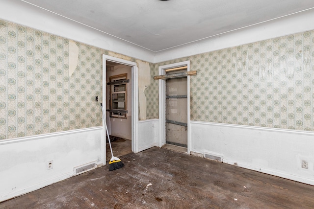 empty room with visible vents, a wainscoted wall, and wallpapered walls