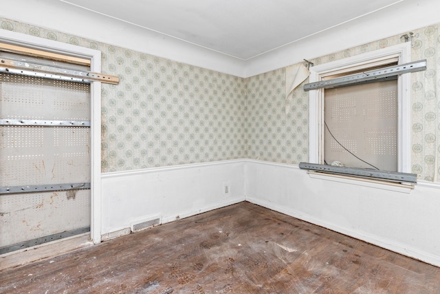 unfurnished room featuring visible vents and a wainscoted wall