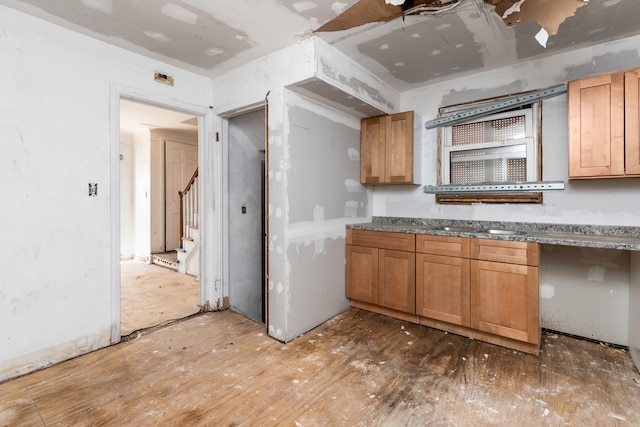 kitchen with a sink, brown cabinetry, and dark stone counters