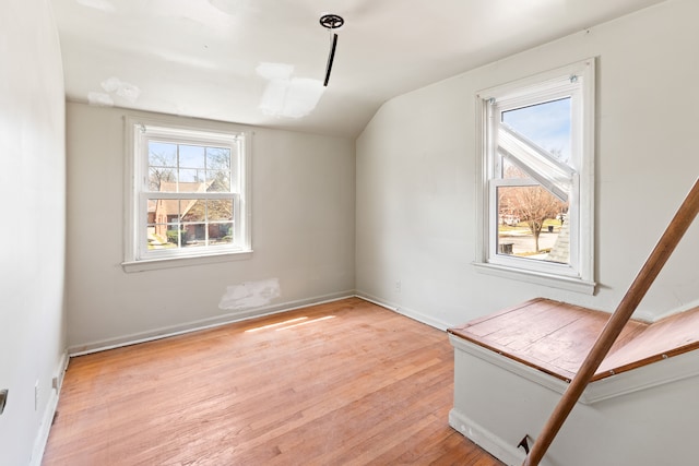 interior space featuring light wood-type flooring, baseboards, and vaulted ceiling