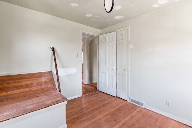 unfurnished bedroom with wood finished floors, baseboards, and visible vents