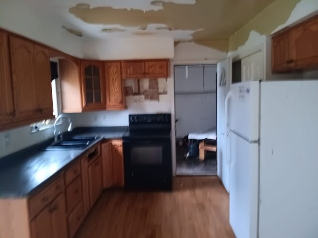 3508 Easthampton Dr, Flint, MI 48503 - kitchen featuring a sink, freestanding refrigerator, black electric range, glass insert cabinets, and wood finished floors