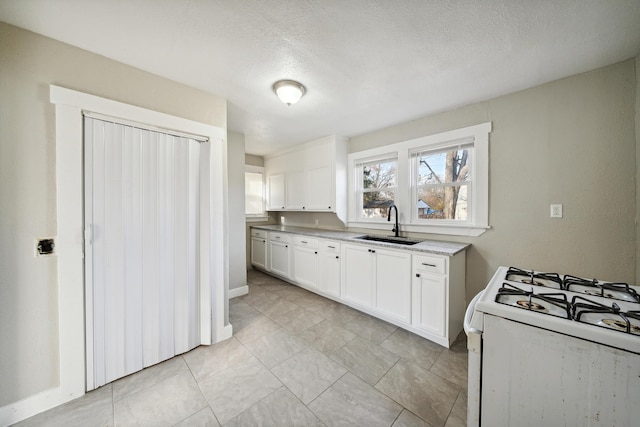 20035 Santa Barbara Dr, Detroit, MI 48221 - kitchen featuring a textured ceiling, white gas stove, a sink, and white cabinets