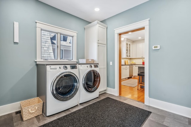 laundry room featuring baseboards, cabinet space, independent washer and dryer, and recessed lighting